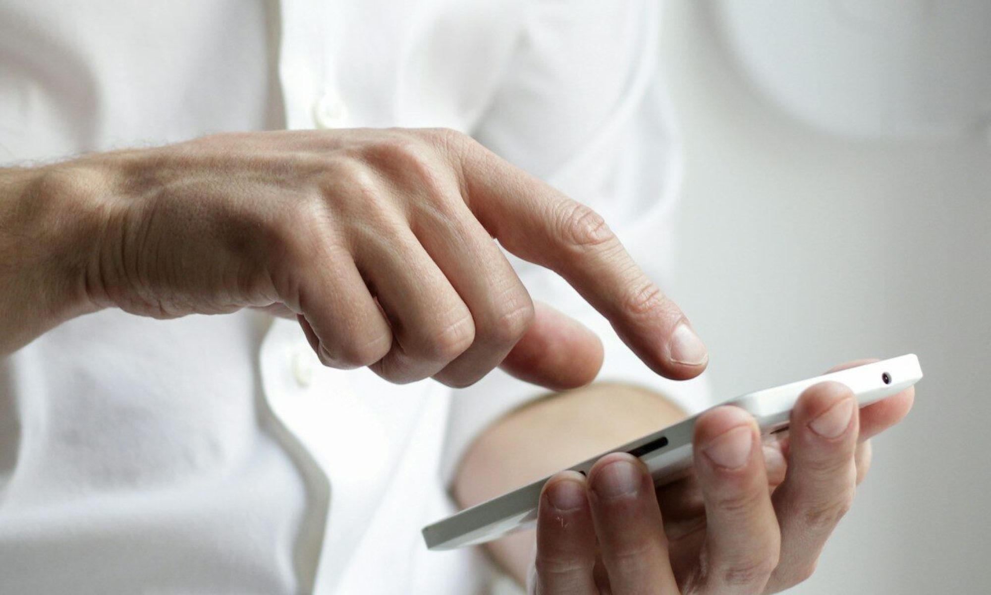 Hombre vestido con ropa de oficina revisando su teléfono móvil